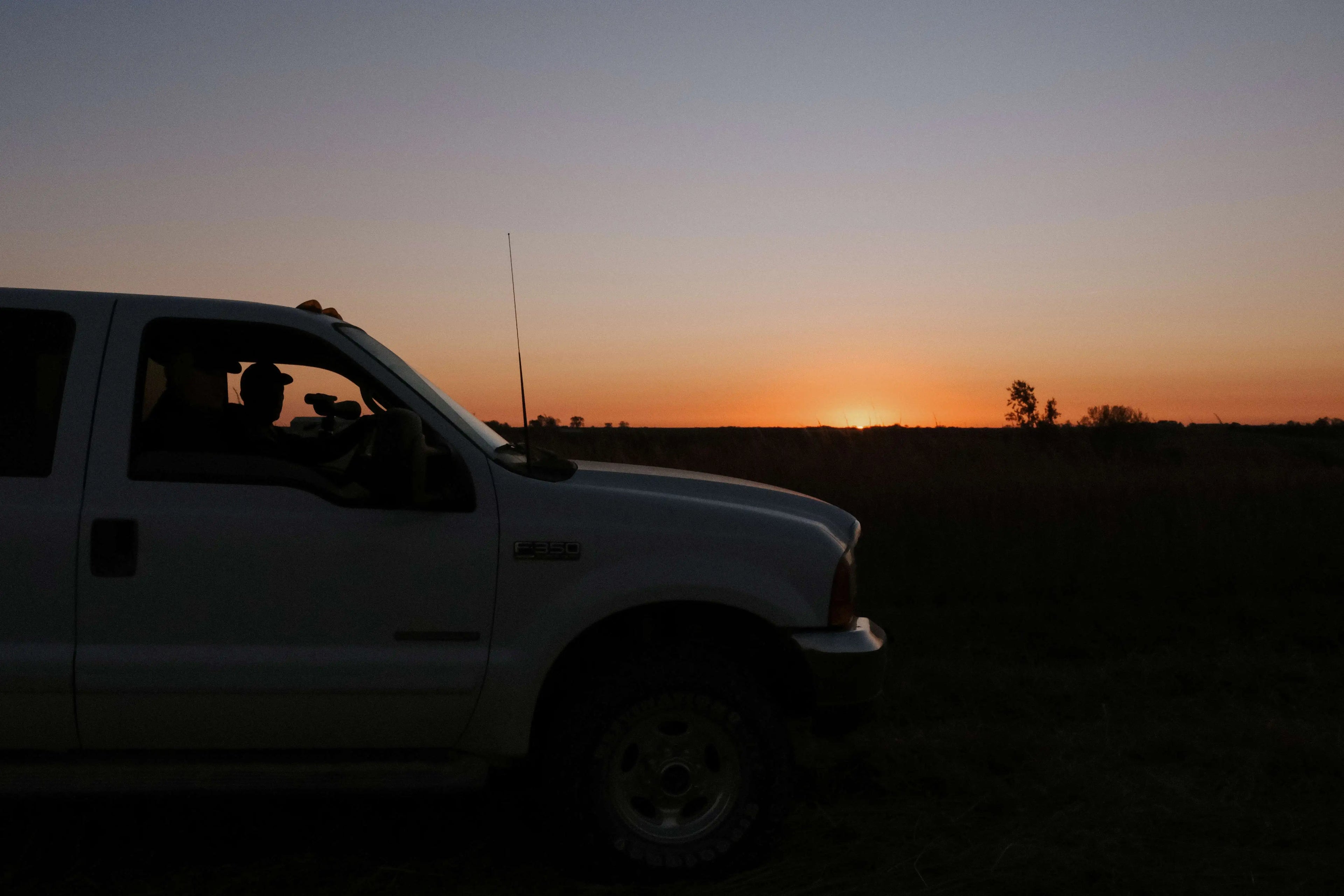 Pickup Truck In Field At Sunrise With Hunters Glassing Inside