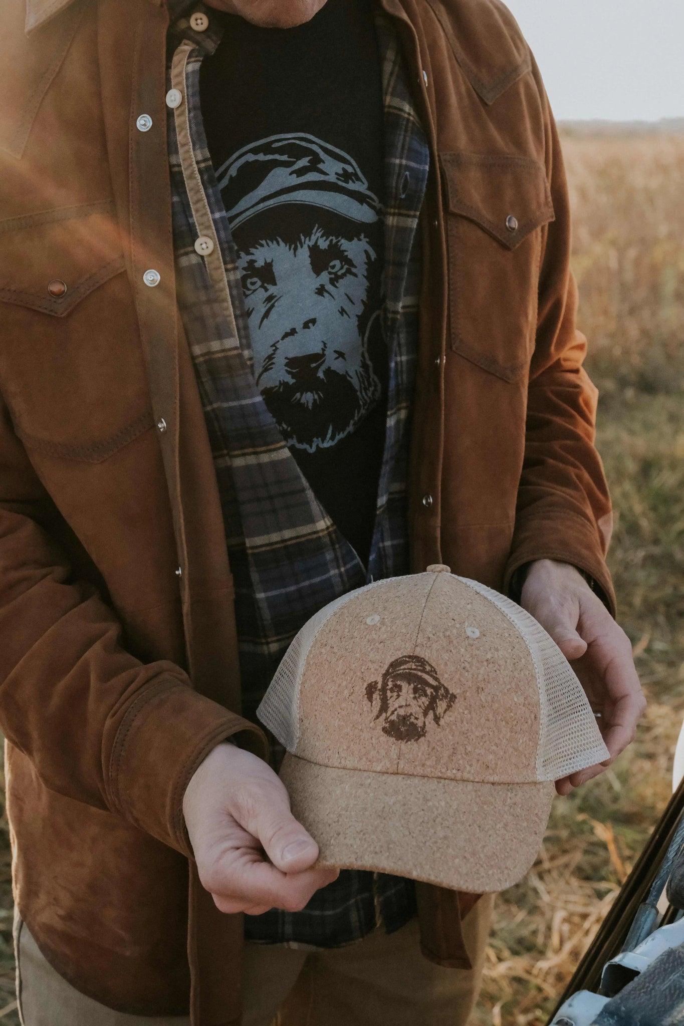 Hunter In Field Holding Cork Hat With Hunt Mutt Dog Logo