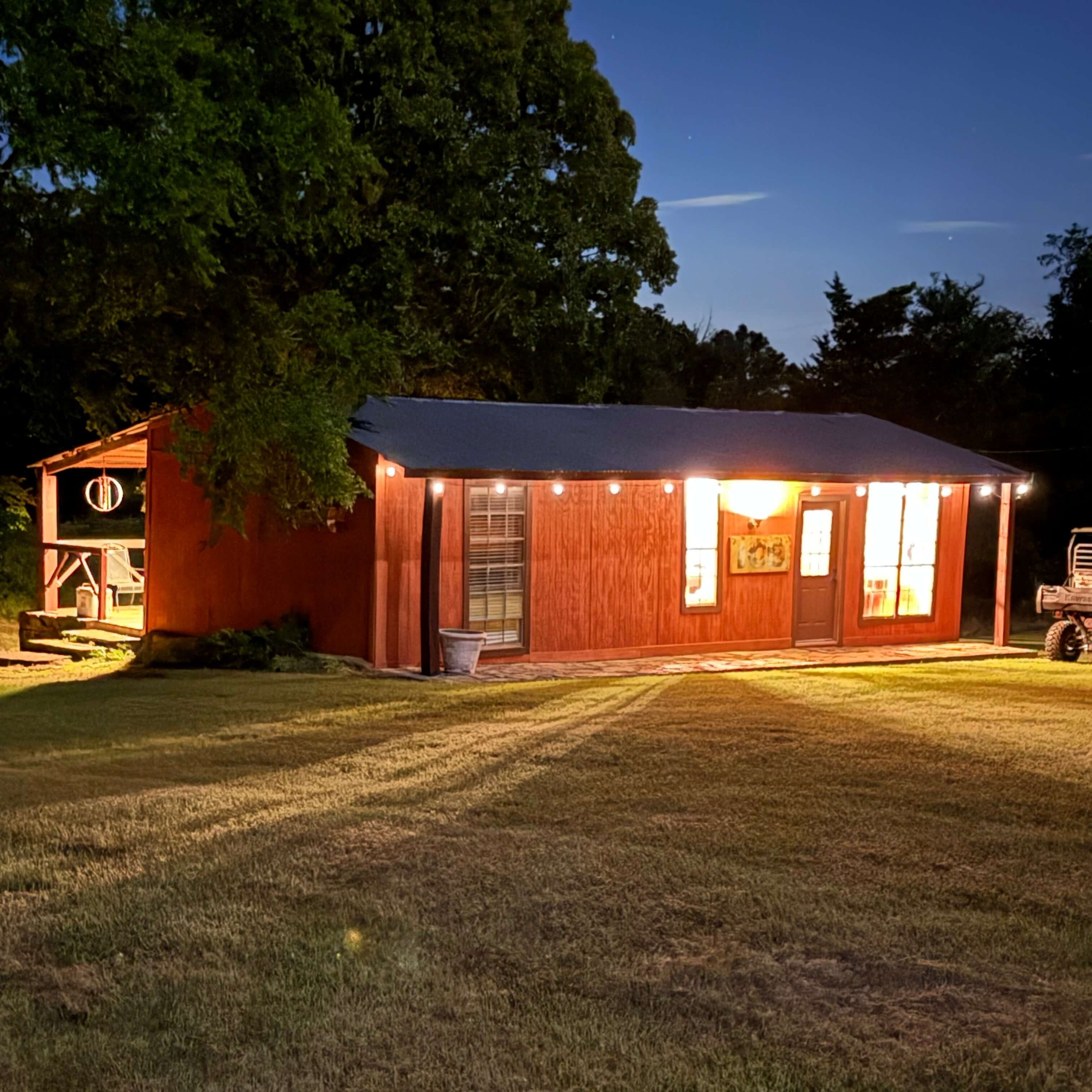 Small building with string lights at night surrounded by trees